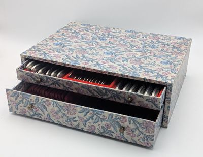 a box that has a drawer full of hair brushes in it
