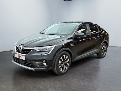 Une voiture noire est garée dans une grande pièce au sol noir.