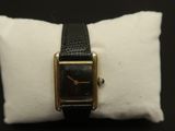 an image of a black and gold watch on a white pillow