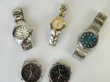 four watches are sitting on a white surface with a white background
