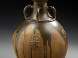 un vase marron posé sur une table sur fond noir