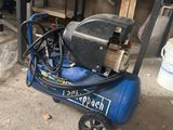 un compresseur d'air bleu posé sur un chariot dans un garage