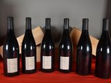 six bottles of wine are lined up on a red cloth