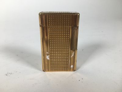 un gros plan d'un briquet doré posé sur une surface blanche