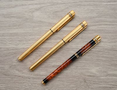 three different types of pens sitting on top of a wooden table
