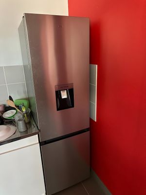 a stainless steel refrigerator in a kitchen with a red wall