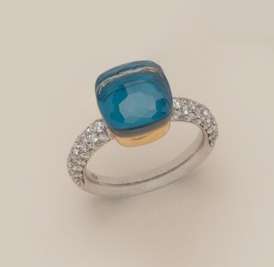 gros plan d'une bague avec une pierre bleue entourée de diamants