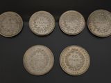 six different types of silver coins are displayed in a display case