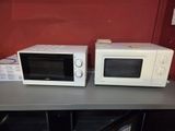 two microwaves that are sitting on a table