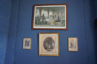 des tableaux accrochés au mur d'une pièce bleue où sont accrochés d'autres tableaux