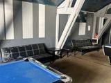 une table de billard au milieu d'une pièce où se trouvent des chaises et une échelle