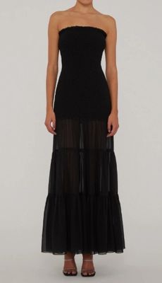La femme en robe noire prend la pose devant l'appareil photo.