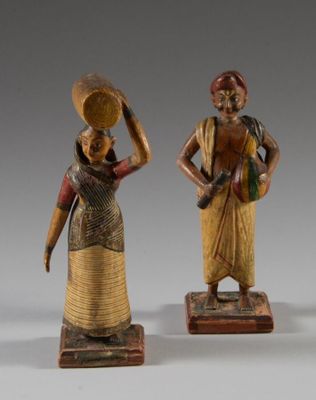 trois figurines en bois représentant des femmes portant des paniers sur la tête
