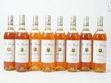 six bouteilles de vin sont alignées sur une surface blanche