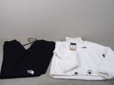 deux paires de vêtements blancs et noirs posées sur un lit
