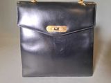 a black leather handbag with a gold clasp on the handle