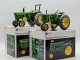 three toy tractors sitting on top of boxes on a table