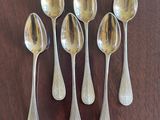 six spoons are lined up on a table with a wooden surface