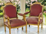 une paire de chaises rouges et dorées placées devant une grande fenêtre