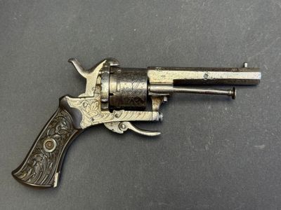un revolver argenté avec une crosse noire sur un fond gris