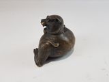 a small bronze statue of a bear sitting on its back