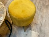 un tabouret jaune et une table ronde posés sur un parquet