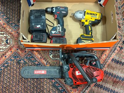 une caisse contenant des outils et une tronçonneuse, posée sur un tapis
