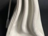 a close up of a white purse on a black surface