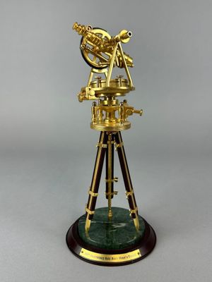 a gold plated telescope on a wooden stand with a green marble base