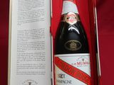 an open box with a bottle of champagne in it on a red cloth