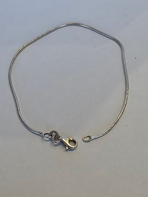 un bracelet à chaîne en argent avec un fermoir, posé sur une surface blanche
