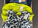 three pairs of jeans and a sweater in a cardboard box