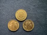 three different types of gold coins on a blue cloth