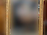un cadre ancien doré avec un miroir, posé sur une table devant un mur rouge