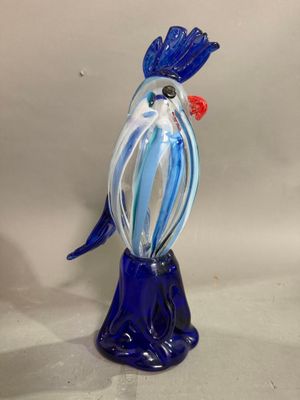un oiseau en verre posé sur un vase bleu