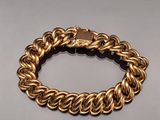 a close up of a gold chain bracelet on a white surface
