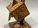 a small clock that is on a stand on a white surface