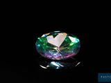 un gros plan d'un diamant vert et violet sur une surface noire