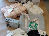 une pile de vêtements de bébé posée sur une table à côté d'une valise