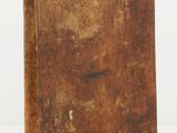 an old book sitting on top of a table next to a white wall