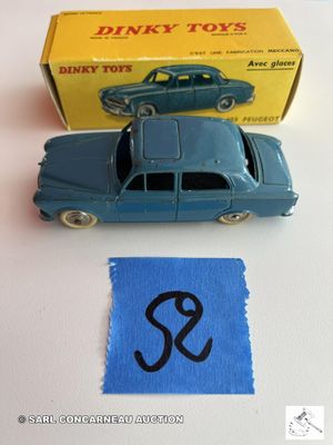 une petite voiture bleue posée à côté d'une boîte de Dinky Toys