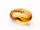 a yellow sapphire stone on a white surface