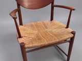 a wooden chair with a woven seat on a grey background