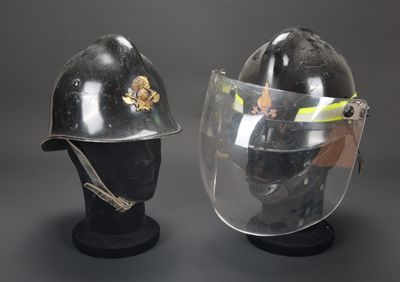 une paire de casques avec visière, exposés sur un fond gris