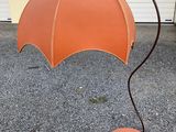 an orange umbrella that is on a stand on the ground