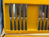 five knives in a yellow box on a table