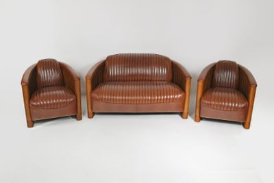 deux fauteuils en cuir marron et un canapé en cuir marron posés sur un sol blanc