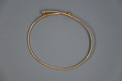 gros plan d'un bracelet en or sur une surface grise