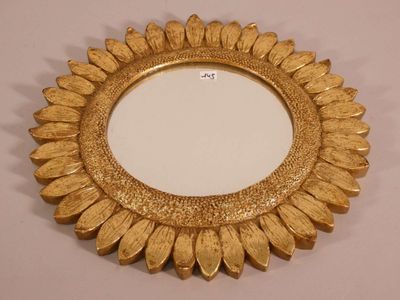 a close up of a gold mirror on a white surface