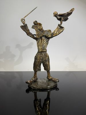 statue of a man holding a sword and a bird on a table